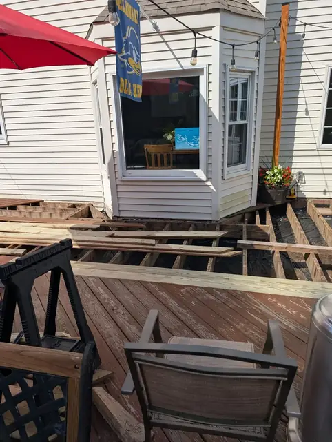 Weathered deck with boards lifted for access, worn grey and brown finish