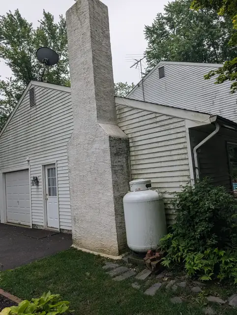 Stucco chimney and garage darkened with algae and staining